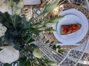 Domus Olea في بوليكاسترو بوسينتينو: طبق مع شريحة من البيتزا على طاولة مع الزهور