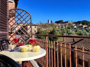 a table with two glasses of wine on a balcony at Lovely Balcony San Gimignano Apartments in San Gimignano