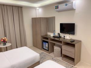 ワディ・ムーサにあるBeit Alshabaan Innのベッド、デスク、テレビが備わるホテルルームです。