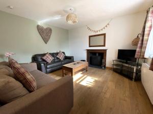 ein Wohnzimmer mit einem Sofa und einem Kamin in der Unterkunft Old Springwell Croft in Onich
