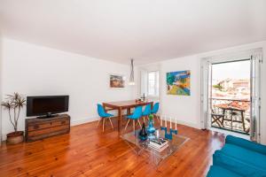 ein Wohnzimmer mit einem Tisch, Stühlen und einem TV in der Unterkunft Rossio - Chiado | Lisbon Cheese & Wine Apartments in Lissabon