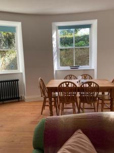 a dining room with a table and chairs and two windows at The Courtyard Apartment, Strangford in Strangford
