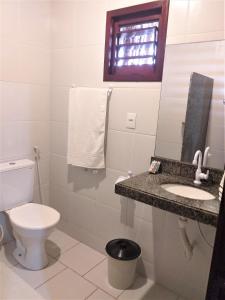 a bathroom with a toilet and a sink and a mirror at Chalés Hibiscus Pipa - ar, cozinha e banheiros privados, estacionamento interno in Pipa