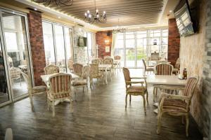 una sala da pranzo con tavoli, sedie e finestre di семеен хотел Прованс Ахелой ad Aheloy