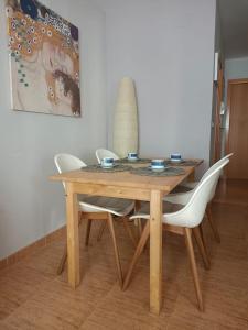 una mesa de madera con 4 sillas blancas alrededor en Les Palmeres Centre, en Les Cases d'Alcanar