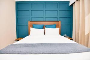 a bedroom with a blue wall and a bed at Unit 508 at Menlyn Place in Pretoria