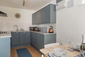une cuisine avec des placards gris et une table en bois dans l'établissement Coedrath Park 20 - Modern Apartment, Close to the Beach, à Saundersfoot