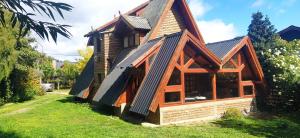 a wooden house with a gambrel roof at Habitacion privada en cabaña compartida "Los Cordobeses" in San Martín de los Andes