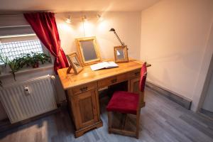 einen Schreibtisch mit einem Spiegel und einem roten Stuhl in der Unterkunft Ferienwohnung zur alten Post in Bad Grund