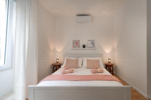 a white bed with two pink stuffed animals on it at Apartment Brandesa in Korčula