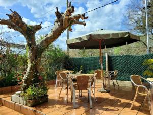 eine Terrasse mit einem Tisch, Stühlen und einem Sonnenschirm in der Unterkunft A CONDA in Arzúa