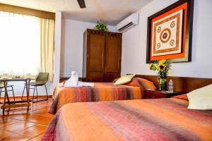 a hotel room with three beds with a cat sitting on them at Hotel Los Girasoles in Cancún +18 photos