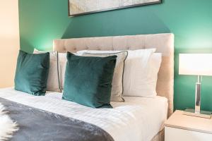 um quarto com uma cama com almofadas verdes e brancas em *KING BED* LUXURY CITY CENTRE HOUSE em Barrow in Furness