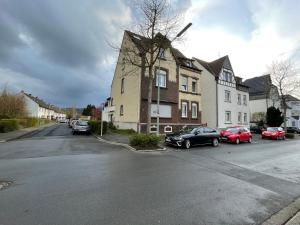 a street with cars parked in front of a house at Suite Dilara by NINJA SPACES - 105QM Maisonette, Garten, Parkplatz in Arnsberg