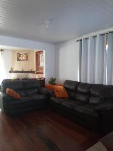 a living room with a black leather couch at Recanto do Sossego in Campos do Jordão