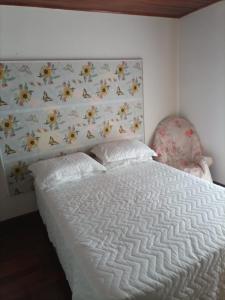 a bedroom with a white bed and a chair at Recanto do Sossego in Campos do Jordão