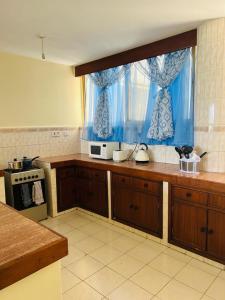a kitchen with wooden cabinets and a blue curtain at Swan Lakeview 2 Apartment with WiFi,Netflix Free Parking,Sunset,Lakeview in Kisumu