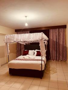 1 dormitorio con 1 cama con dosel en Swan Lakeview 2 Apartment with WiFi,Netflix Free Parking,Sunset,Lakeview en Kisumu