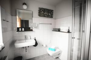 a white bathroom with a sink and a toilet at Pension Mai-Scholle in Borkum