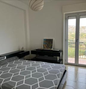 a white bedroom with a bed and a window at A'mare in Siculiana Marina