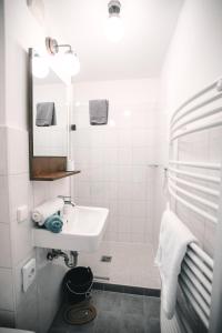 a white bathroom with a sink and a mirror at Pension Mai-Scholle in Borkum