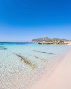 a beach with clear water and mountains in the background at Stabilimento Lido Burrone in Favignana