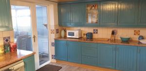 a kitchen with blue cabinets and a microwave at Badger's House, Willow Close, Filey in Filey