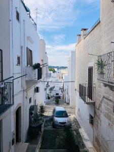 une voiture garée dans une ruelle entre deux bâtiments dans l'établissement Angoletto Bianco, à Ostuni