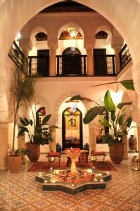 un grand hall avec une table et des plantes dans l'établissement Riad Adriana, à Marrakech