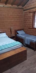 two beds in a room with a brick wall at Chalés Portal Verde - Seja bem vindo in Carrancas