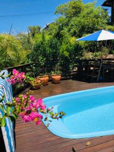 una piscina en una terraza con flores y sombrilla en Residencial Vila Suel, en Praia do Rosa