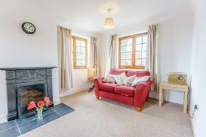 a living room with a red couch and a fireplace at Little Melrose in Yalding
