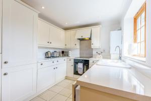 a white kitchen with white cabinets and a sink at Little Melrose in Yalding