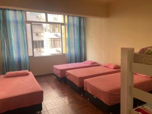 um quarto com três camas e uma janela em Apartamento de Copacabana ( Posto 5 ) no Rio de Janeiro