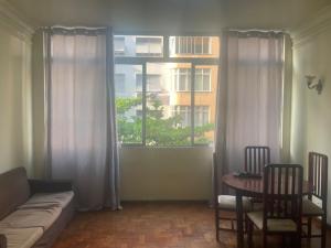 een woonkamer met een bank, een tafel en een raam bij Apartamento de Copacabana ( Posto 5 ) in Rio de Janeiro