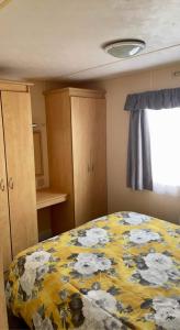 1 dormitorio con 1 cama con manta amarilla y blanca en dees caravan lettings kingfisher elm 453, en Ingoldmells