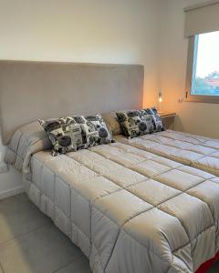 un grande letto con cuscini sopra in una camera da letto di Administración MAIPU 3B FI DEPTO PREMIUM a Tandil