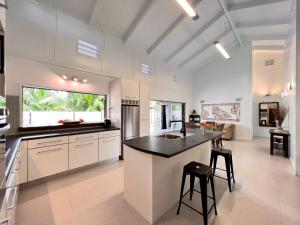 a kitchen with white cabinets and a black counter top at Sina Pool Villa Rarotonga in Arorangi