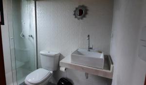 a white bathroom with a sink and a toilet at IbiraCottage in Imbituba +28 photos