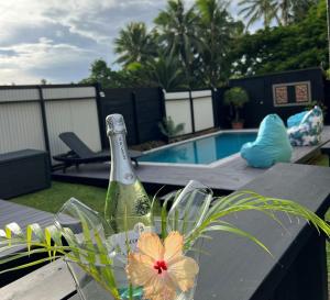 a bottle of champagne sitting on a table with a flower at Sina Pool Villa Rarotonga in Arorangi