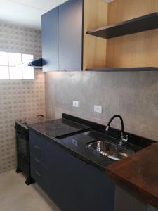 - une cuisine avec un plan de travail noir et un évier dans l'établissement Flat Vila Caiçara, à Ilhabela