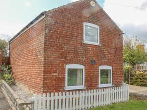 a brick house with two windows and a white fence at The Granary in Great Driffield