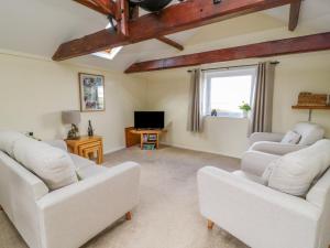 a living room with white couches and a tv at The Granary in Great Driffield