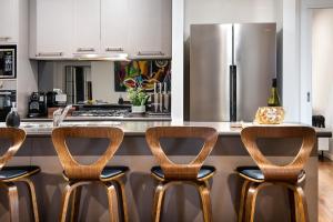 a kitchen with a counter with four chairs and a refrigerator at Manna Gums in Daylesford