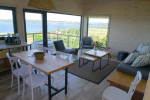 Una sala de estar con mesa y sillas y ventanas. en Parcela Nueve, en Frutillar