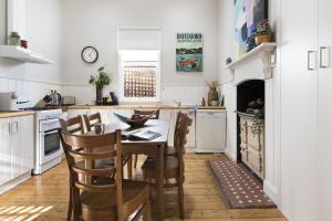 una cucina con tavolo e sedie in una cucina di Albert Cottage - charming miner's cottage in town a Daylesford
