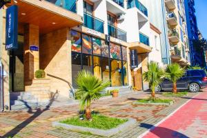 a street with palm trees in front of a building at EMEG Hotel and Restaurant in Batumi