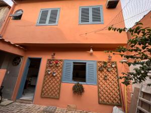 an orange building with blue shutters and a window at Hostel El Caminito LGBTQIAPN plus in Santos