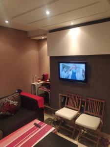 uma sala de estar com um sofá e uma televisão na parede em Appartement avec piscine a Dreamland Sidi Rahal em Sidi Rahal