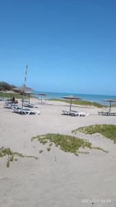 uma praia com alguns guarda-sóis e cadeiras em Appartement avec piscine a Dreamland Sidi Rahal em Sidi Rahal